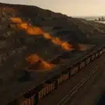 Mina a céu aberto e linha ferroviária em imagem editorial sobre mineração brasileira e superávit comercial.